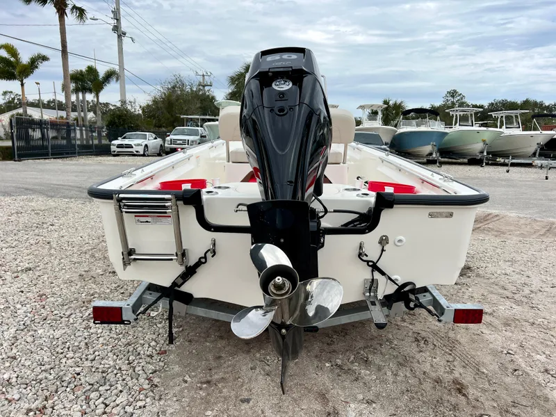 Slide: The Image of 2025 Boston Whaler 150 Montauk boat, rear view with outboard motor, parked on gravel. - 7