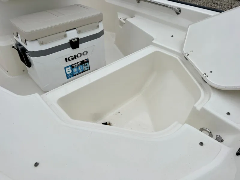 Slide: The Image of 2025 Boston Whaler 150 Montauk interior with Igloo cooler and storage compartment. - 9