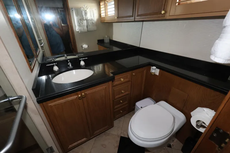 Slide: The Image of Luxurious bathroom in 1988 Broward 124 Tri-Deck MY yacht with wood cabinetry and black countertops. - 46