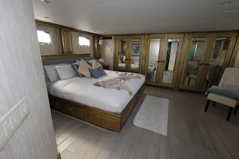 Slide: The Image of Luxurious bedroom on 1988 Broward 124 Tri-Deck MY yacht with elegant decor and mirrored closets. - 47