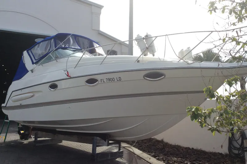 The Image of 2000 Maxum 2800 SCR boat with blue canopy, docked near a building. - 1