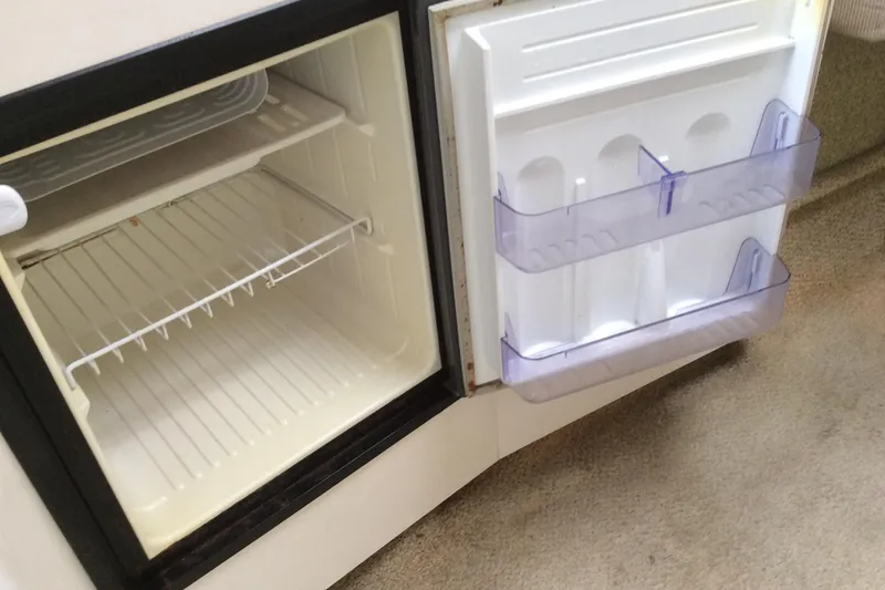 Slide: The Image of Open refrigerator inside a 2000 Maxum 2800 SCR boat, showing empty shelves and door compartments. - 19