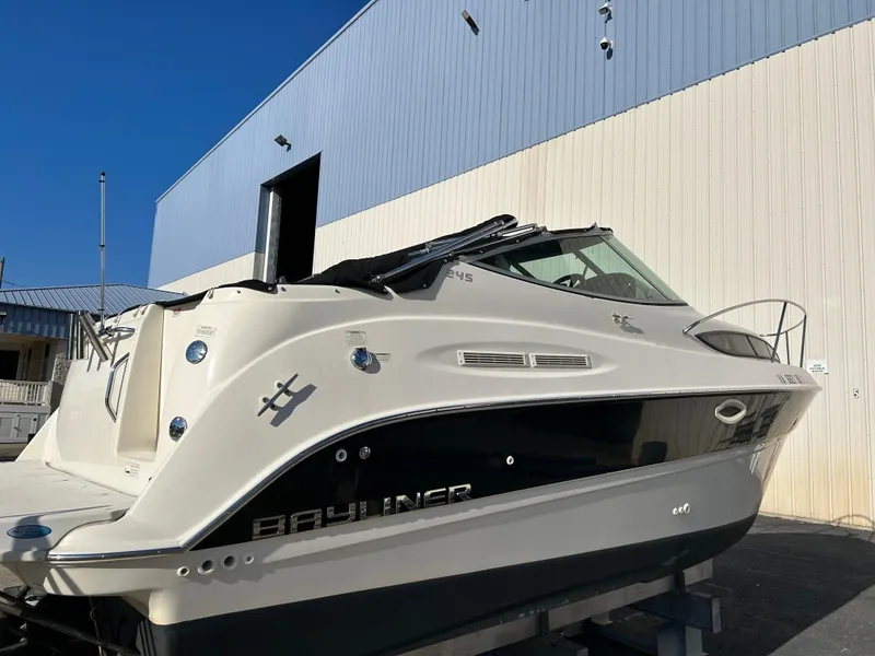 Slide: The Image of 2013 Bayliner 245 Cruiser boat docked near a building under clear blue sky. - 2
