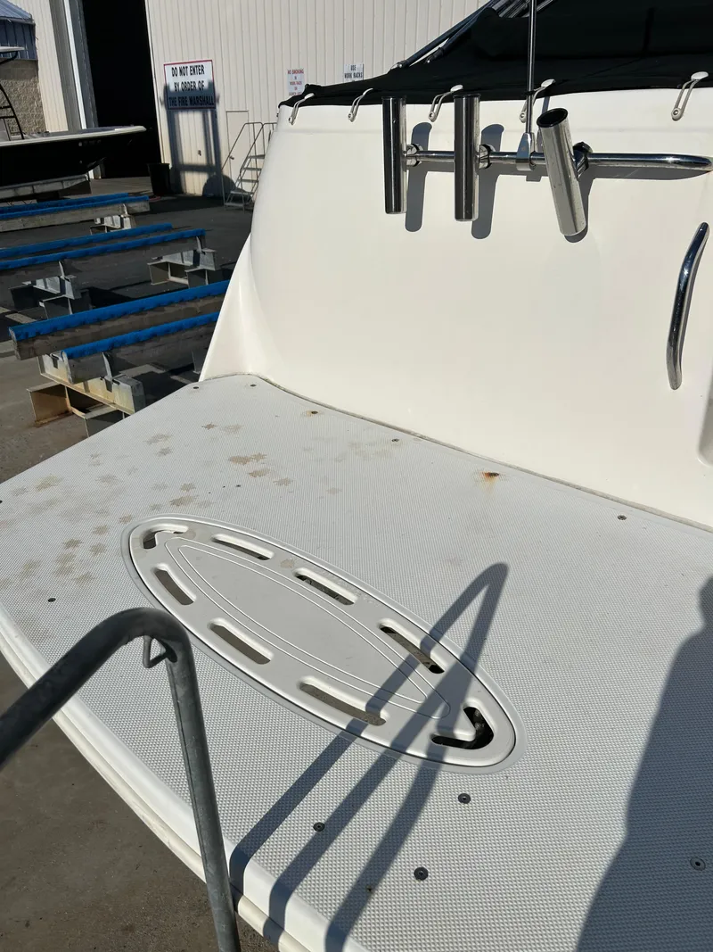 Slide: The Image of 2013 Bayliner 245 Cruiser boat deck with rod holders in a marina setting. - 4