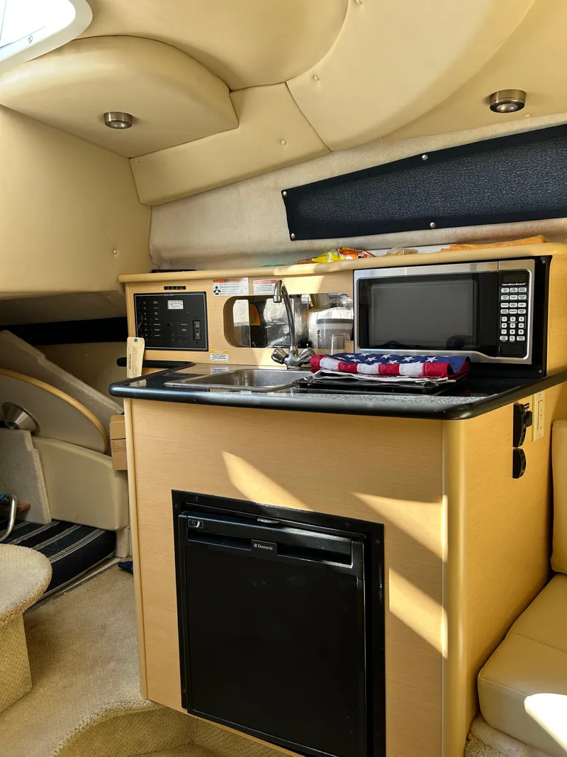 Slide: The Image of Interior of 2013 Bayliner 245 Cruiser with kitchenette, microwave, and compact fridge. - 6