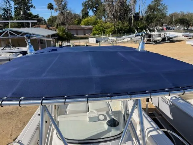 Slide: The Image of Boston Whaler 240 Outrage 2004 with blue canopy in a sunny marina setting. - 13