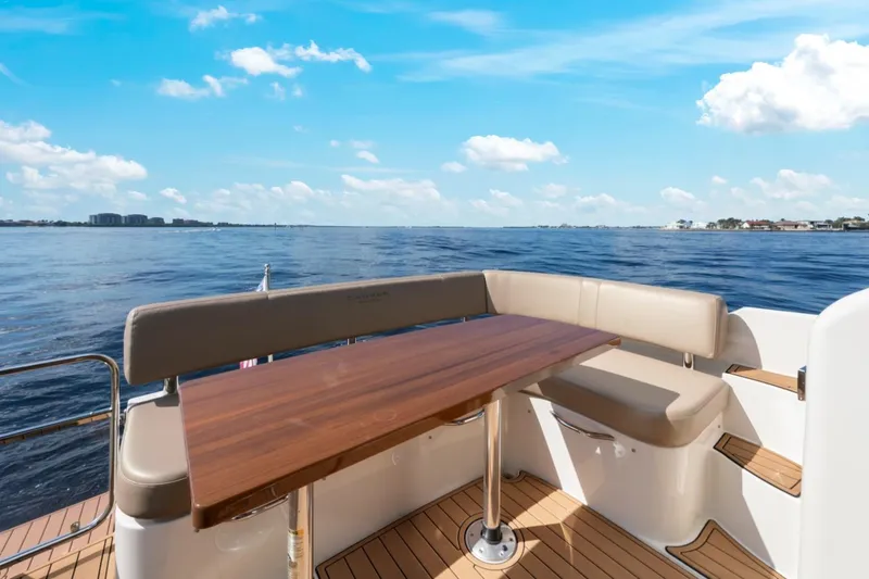 Slide: The Image of 2016 Carver C37 Coupe yacht deck with seating and table, overlooking serene water. - 20