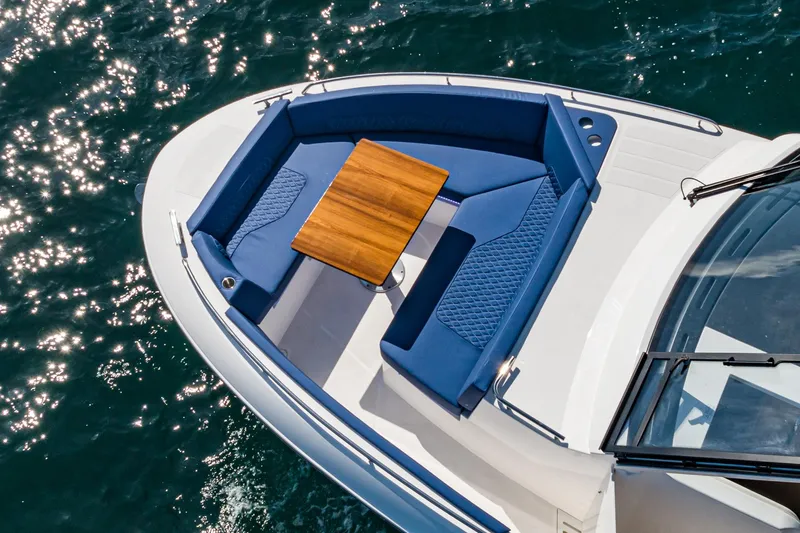 Slide: The Image of Bavaria Vida 33 boat, 2023 model, with blue seating and wooden table on deck. - 24