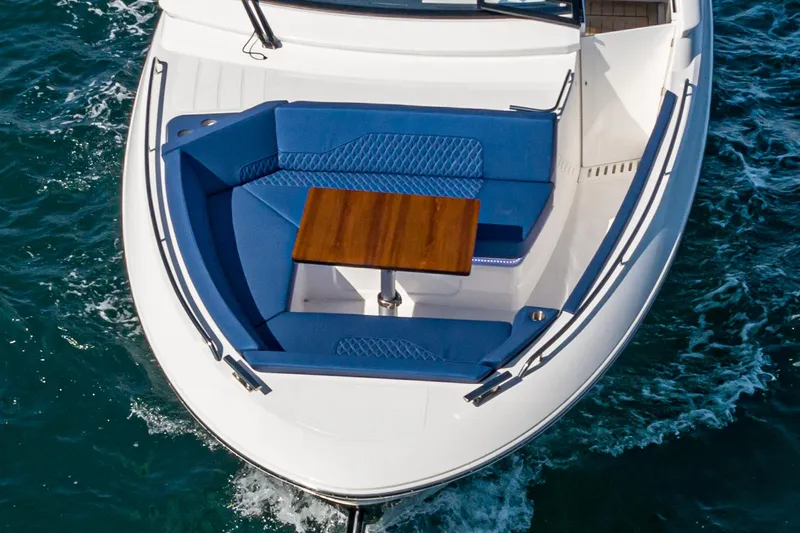 Slide: The Image of Bavaria Vida 33 boat, 2023 model, with blue seating and wooden table on deck. - 25