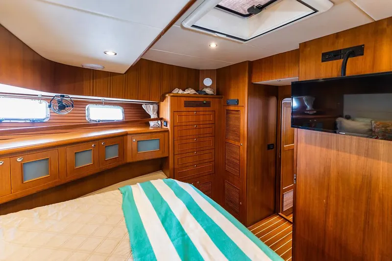 Slide: The Image of Cozy cabin interior of 2016 North Pacific 49 Pilothouse with wood paneling and striped bedding. - 25