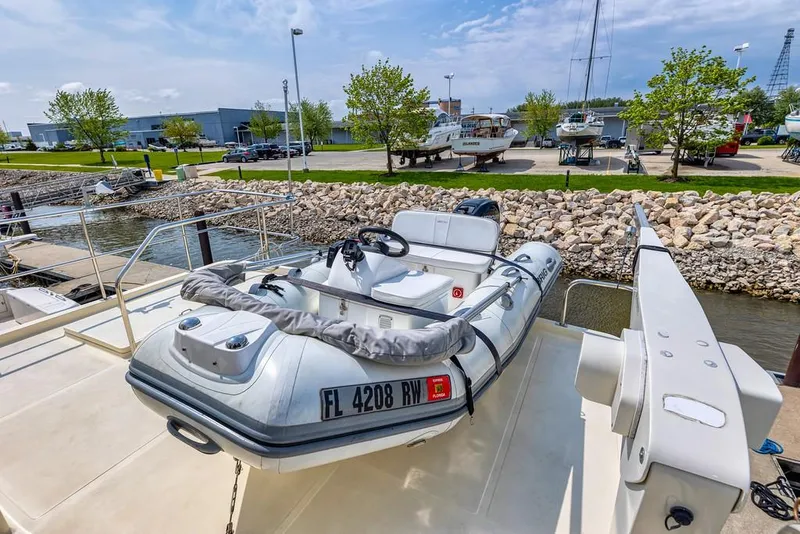 Slide: The Image of 2016 North Pacific 49 Pilothouse with dinghy on deck at marina. - 30