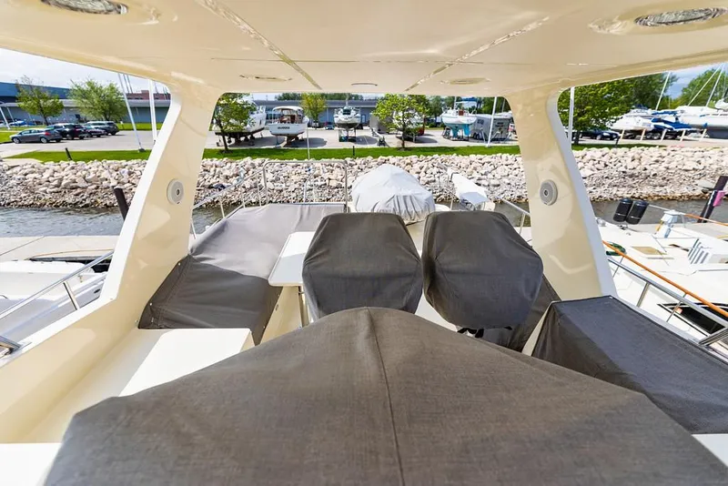 Slide: The Image of 2016 North Pacific 49 Pilothouse yacht deck with covered seating and scenic marina view. - 35