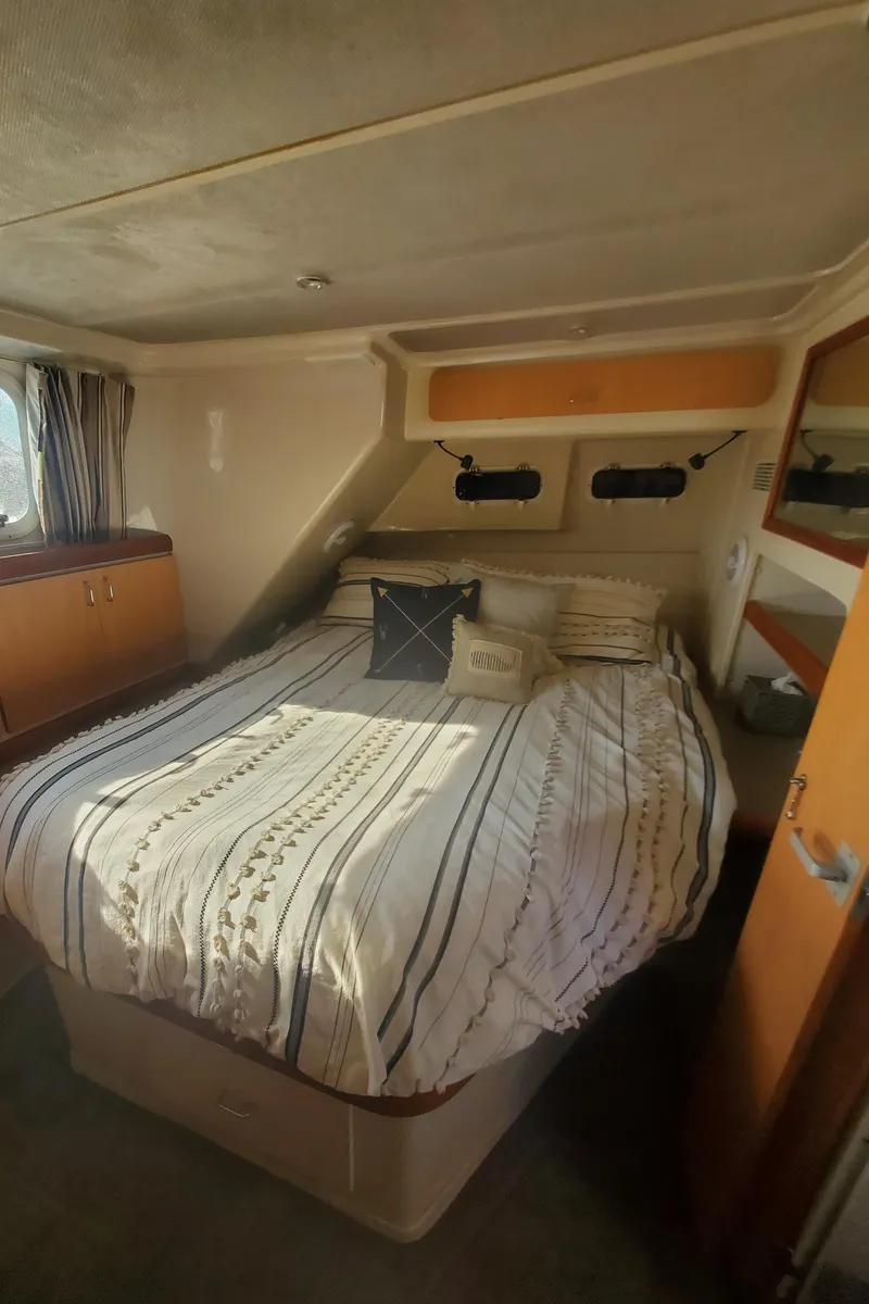 Slide: The Image of Cozy bedroom in 1995 Mainship 37 Motor Yacht with striped bedding and natural light. - 18