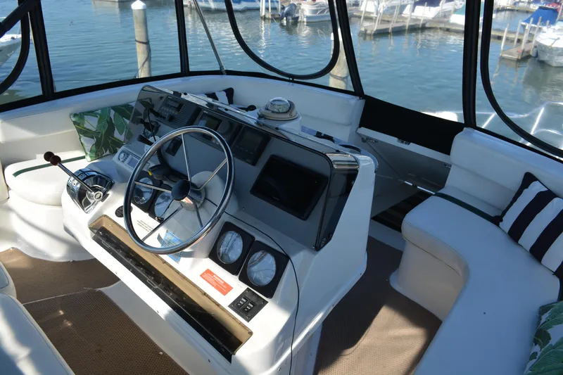 Slide: The Image of 1995 Mainship 37 Motor Yacht helm with steering wheel and gauges, docked at marina. - 8