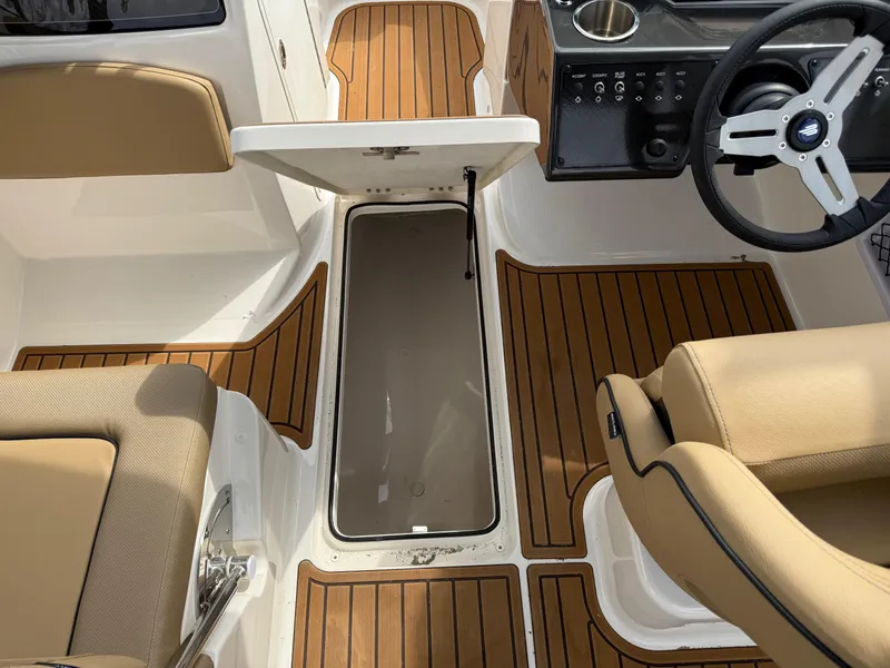 Slide: The Image of 2025 Bayliner VR5 Bowrider OB interior with open storage compartment and tan seating. - 13