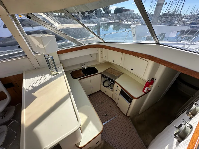 Slide: The Image of 1990 Trojan 46 Flybridge yacht interior with kitchenette and marina view. - 18