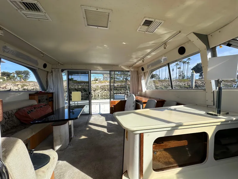 Slide: The Image of Interior of a 1990 Trojan 46 Flybridge yacht with spacious seating and large windows. - 19