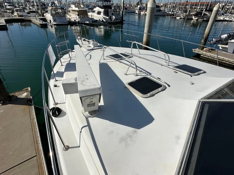 Slide: The Image of 1990 Trojan 46 Flybridge yacht docked in a marina, showcasing spacious deck and sleek design. - 27