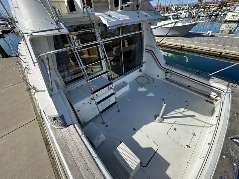 Slide: The Image of 1990 Trojan 46 Flybridge yacht at dock, featuring spacious deck and ladder access. - 28