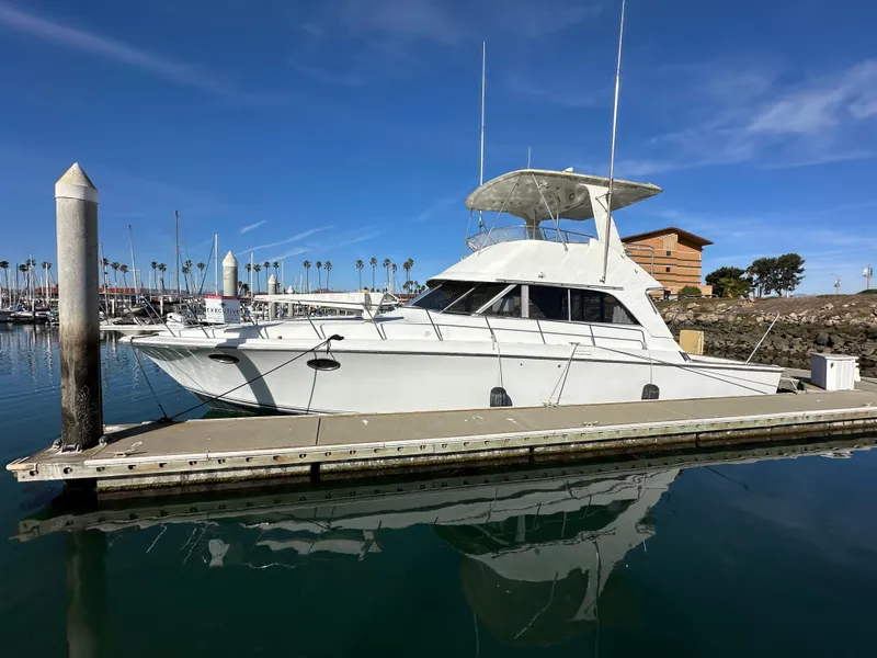 Slide: The Image of 1990 Trojan 46 Flybridge yacht docked at marina under clear blue sky. - 32