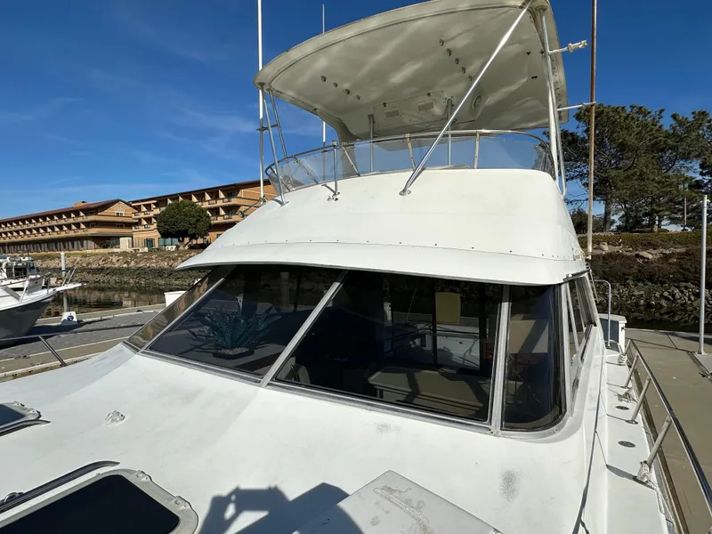 Slide: The Image of 1990 Trojan 46 Flybridge boat with canopy, docked under clear blue sky. - 34