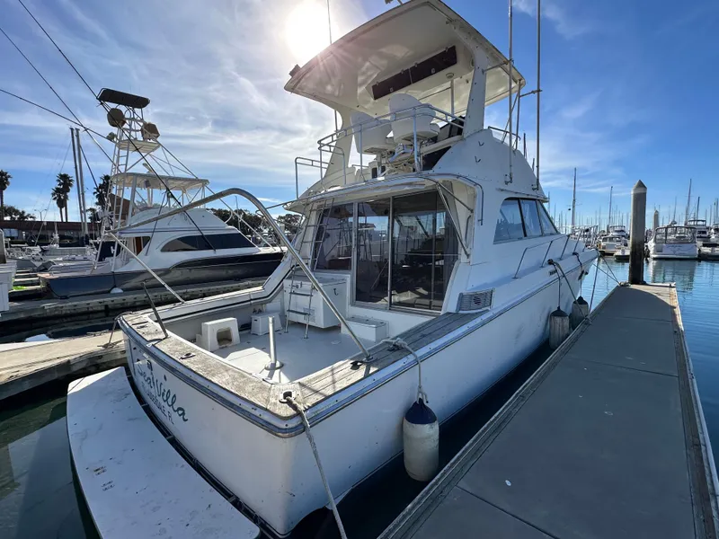 Slide: The Image of 1990 Trojan 46 Flybridge yacht docked at marina under clear blue sky. - 37