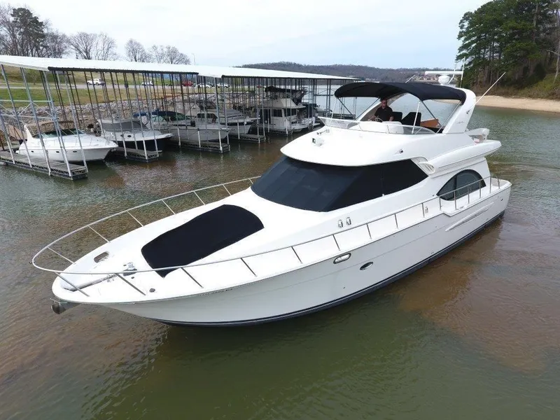 Slide: The Image of 2004 Meridian 540 Pilothouse yacht docked near a marina, surrounded by calm waters. - 0