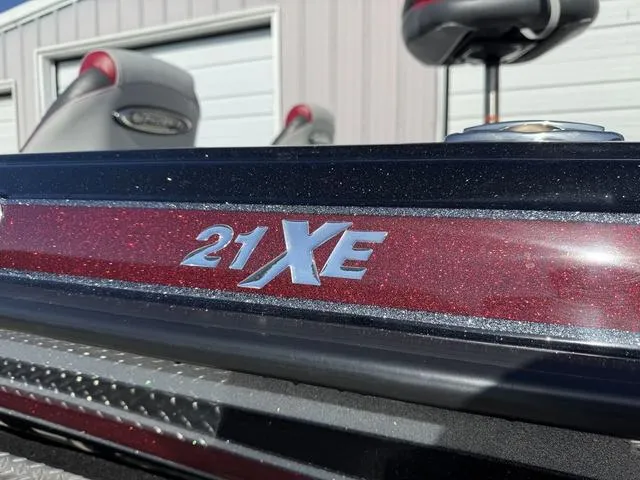 Slide: The Image of 2025 Phoenix 21 XE boat with metallic red detailing, parked near a garage. - 3