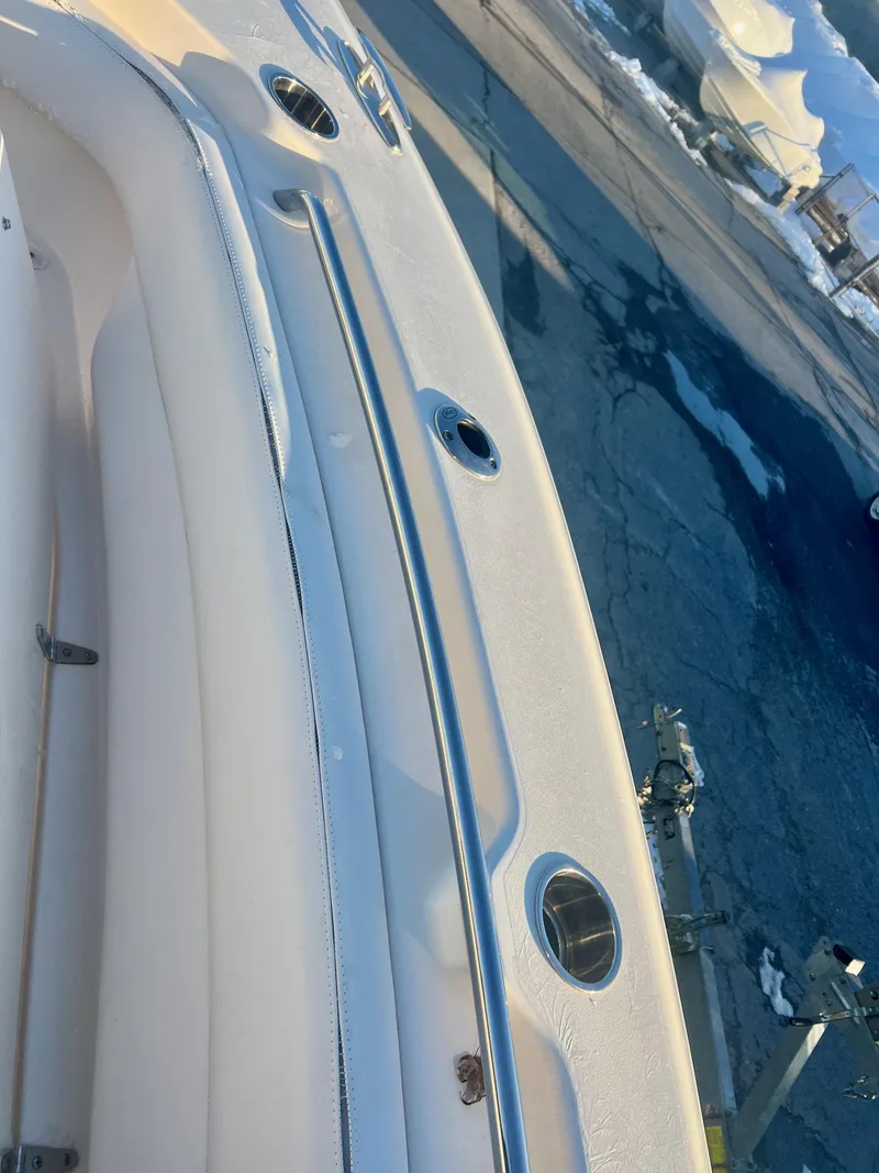 Slide: The Image of 2018 Grady-White Canyon 271 FS boat deck with rod holders, docked by snowy shore. - 33