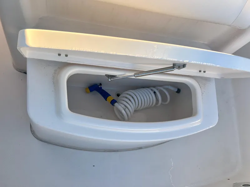 Slide: The Image of 2018 Grady-White Canyon 271 FS boat storage compartment with coiled hose. - 40