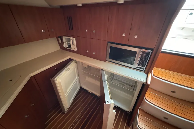 Slide: The Image of 2004 Tiara Yachts 4200 Open kitchen with wood cabinets, microwave, and open fridge. - 33
