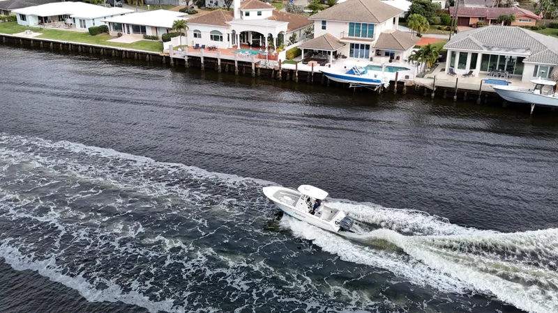 Slide: The Image of Aerial view of 2017 Tidewater 252 LXF boat cruising along waterfront homes. - 4