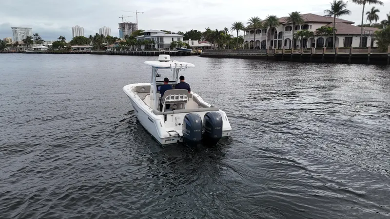 Slide: The Image of 2017 Tidewater 252 LXF boat cruising on a calm waterfront near luxury homes. - 6
