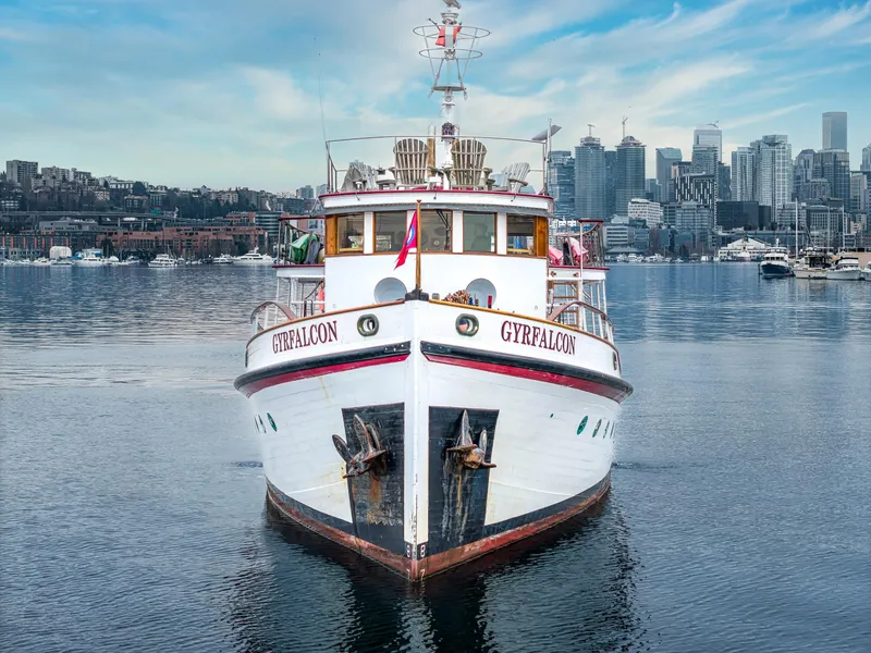 Slide: The Image of Front view of 1941 Custom Sagstad Fantail boat "GYRFALCON" on calm water, city skyline background. - 11