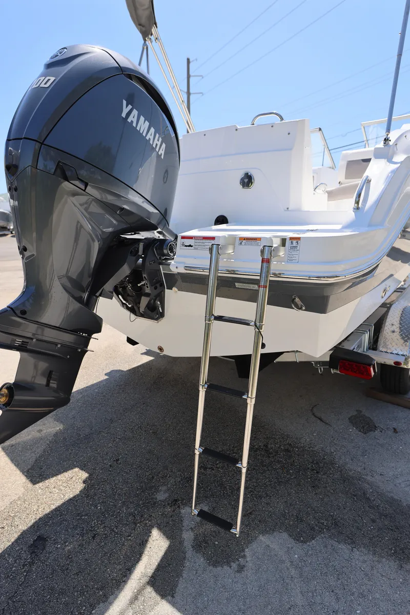 Slide: The Image of 2025 Hurricane SunDeck 235 OB with Yamaha outboard motor and ladder, docked on a sunny day. - 28
