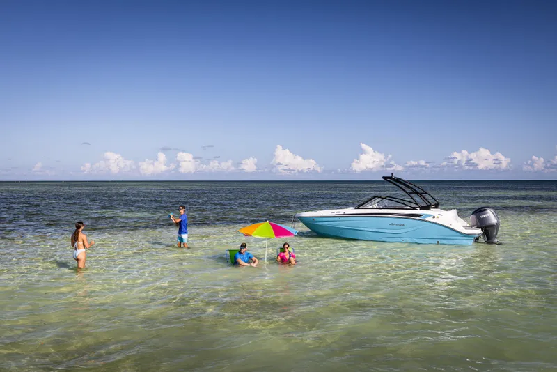 Slide: The Image of 2025 Hurricane SunDeck 235 OB boat anchored near beach with people enjoying the water. - 30