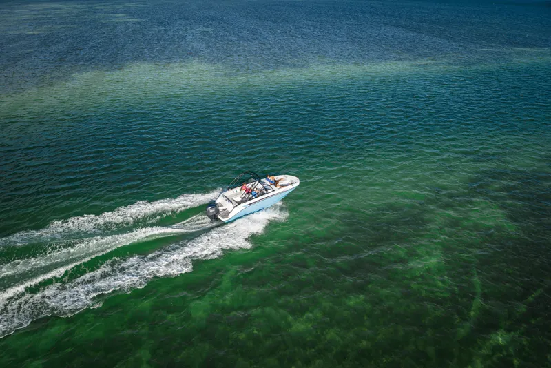 Slide: The Image of Aerial view of 2025 Hurricane SunDeck 235 OB cruising on clear green water. - 35