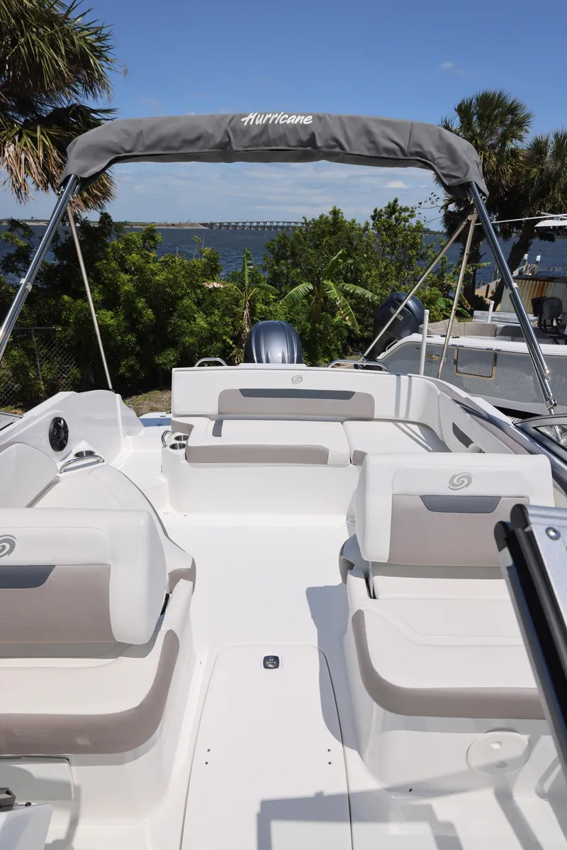Slide: The Image of 2025 Hurricane SunDeck 235 OB boat with spacious seating and canopy, set against a scenic waterfront. - 9