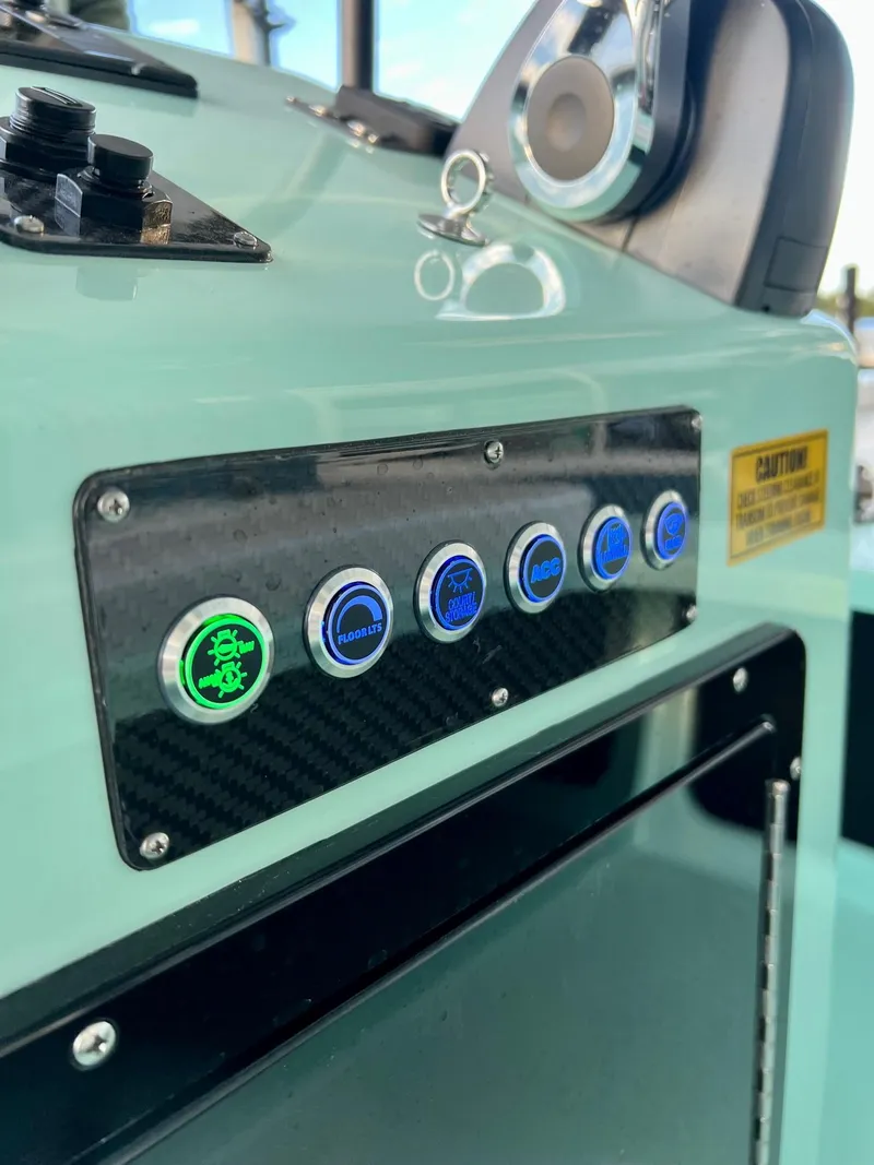 Slide: The Image of Control panel of 2024 Chittum Skiffs Islamorada 18 boat with illuminated buttons. - 7