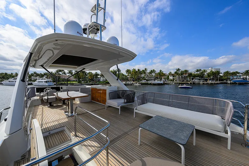 Slide: The Image of Luxurious 2021 Prestige 690 yacht deck with seating, overlooking marina and palm trees. - 2