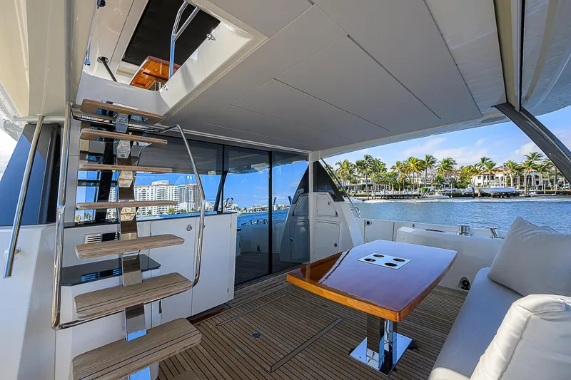 Slide: The Image of Prestige 690 yacht 2021, elegant deck with seating and table, waterfront view. - 20