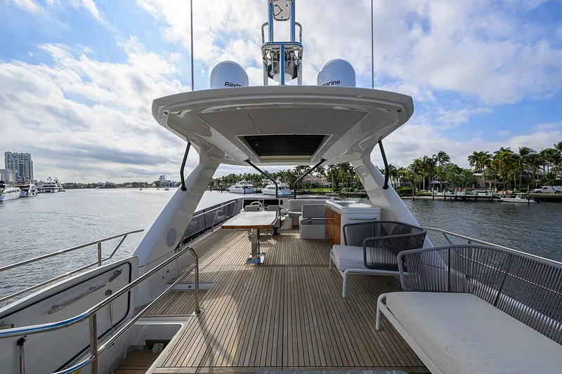 Slide: The Image of Luxurious 2021 Prestige 690 yacht deck with seating, table, and scenic waterfront view. - 28