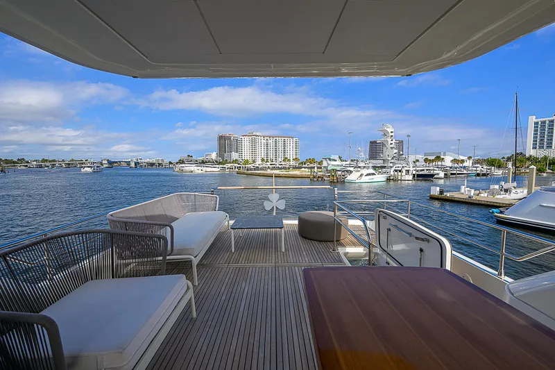 Slide: The Image of Prestige 690 yacht deck with marina view, 2021 model, featuring elegant seating and wooden table. - 29