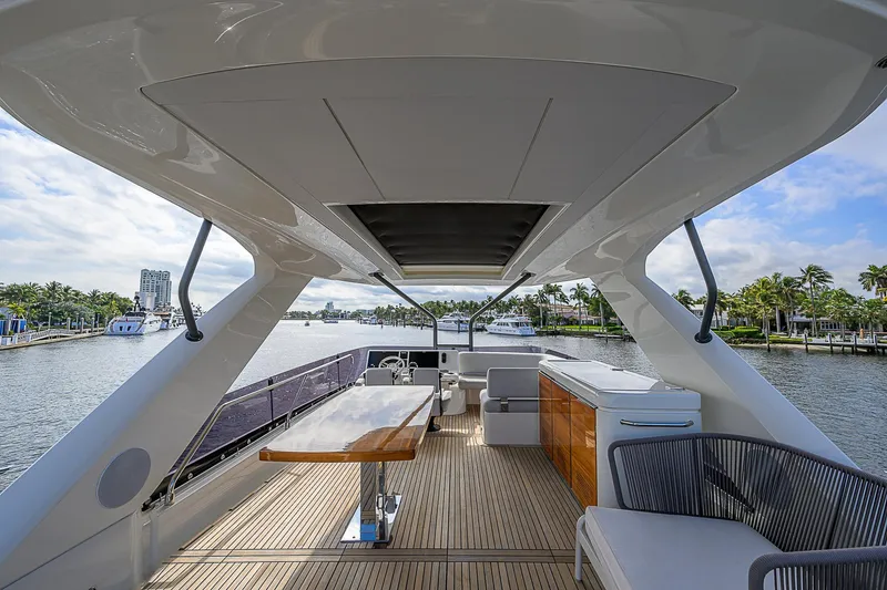 Slide: The Image of Luxurious 2021 Prestige 690 yacht deck with seating and dining area, overlooking serene waterfront. - 32