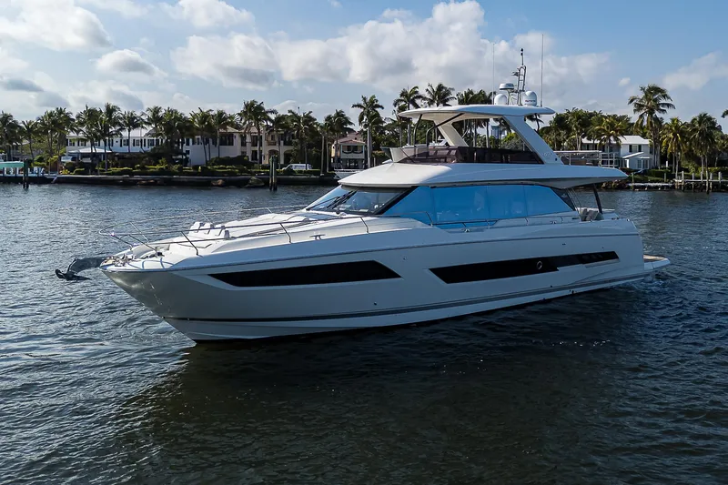 Slide: The Image of Luxury 2021 Prestige 690 yacht cruising on a sunny day near palm-lined shore. - 4