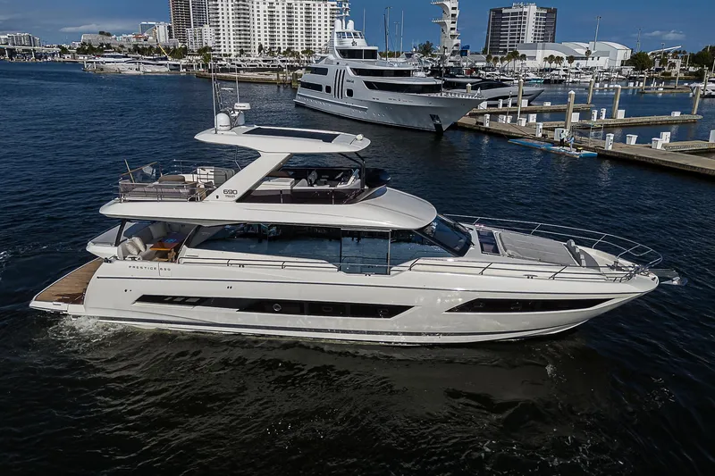 Slide: The Image of Luxury 2021 Prestige 690 yacht cruising in a marina with cityscape background. - 5