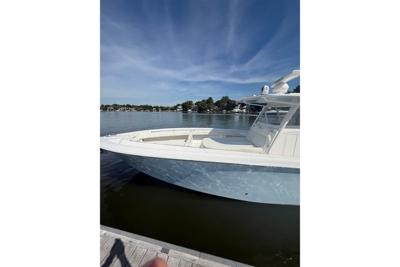Slide: The Image of 2022 Invincible 39 Open Fisherman boat docked on a calm lake under a clear sky. - 2