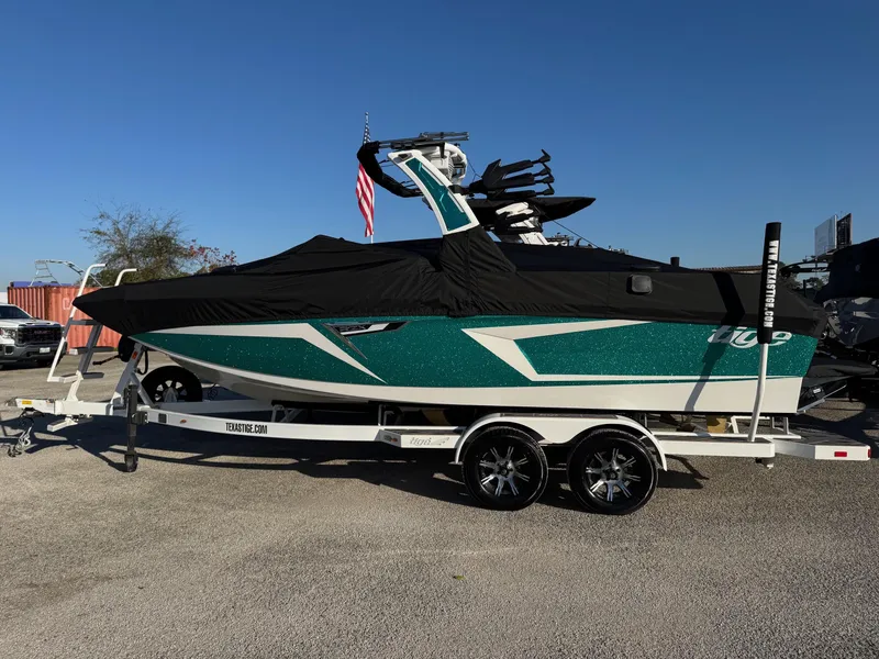 Slide: The Image of 2025 Tigé 22RZX boat on trailer, covered, with American flag in background. - 13
