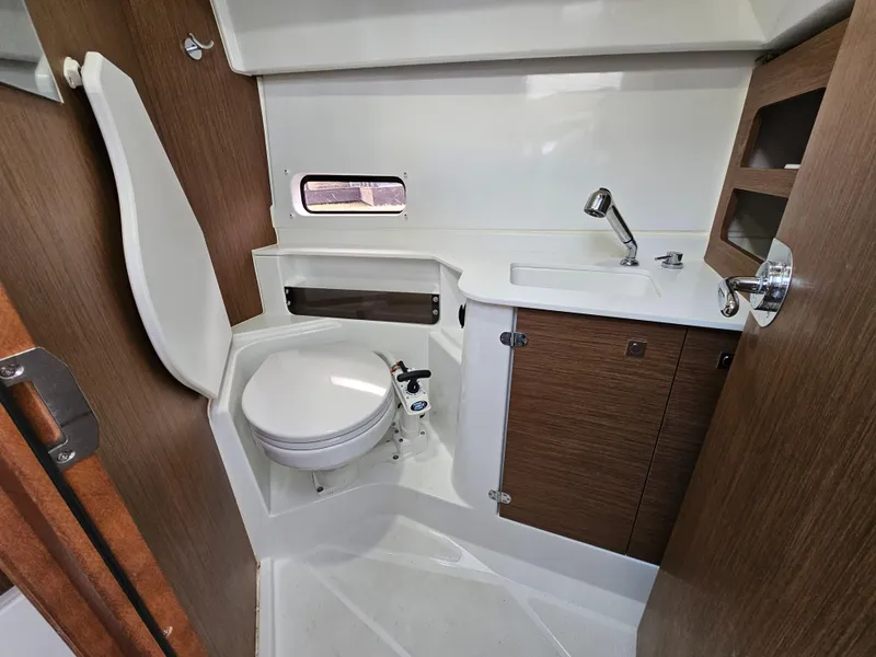 Slide: The Image of 2020 Beneteau Antares 9 bathroom with toilet, sink, and wooden cabinetry. - 10
