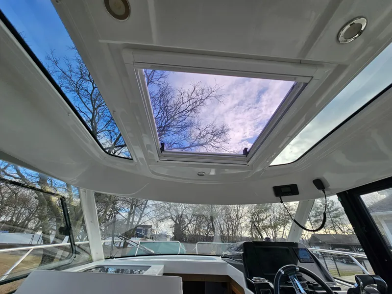 Slide: The Image of Interior view of 2020 Beneteau Antares 9 boat with open sunroof and clear sky. - 12